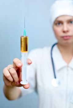 Doctor holding big syringe with yellow liquid, focus on syringe