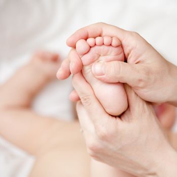 Mother massaging her child's foot, shallow focus