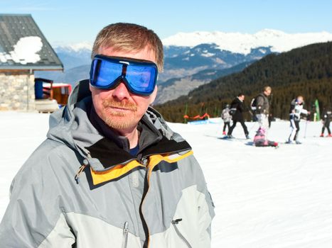 Caucasian mid-adult man in ski goggles posing at Alpine ski resort