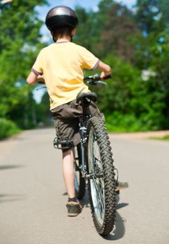 Young boy standing with bicycle, shallow dof, focus on rear wheel