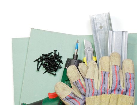 Plasterboard tools set with metal studs, screws, screwgun, cutter and protective gloves on white background