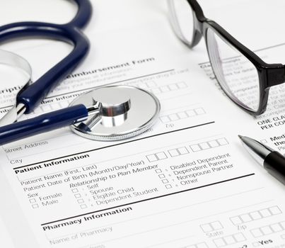 Pen stethoscope and glasses over blank Prescription form with patient and pharmacy information