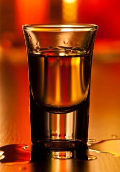 Shot glass of whiskey on a table, shallow focus