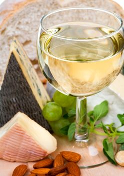 Glass of white wine with cheese at background, shallow DOF