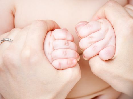 Infant holding mother's hands, shallow focus