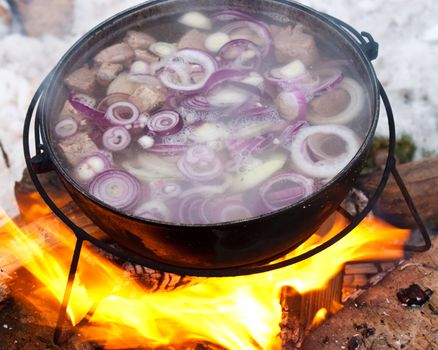 Cooking Chorba soup in cauldron on fire