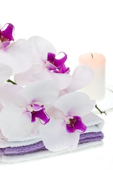 Spa set with white orchid, towels and burning candle on white background