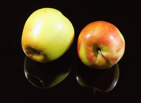Two apples on black background with shadow