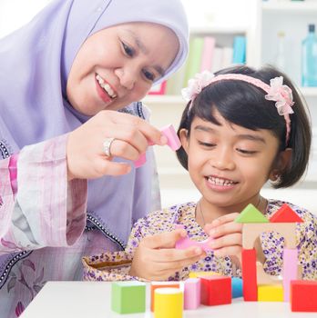 Muslim family building wooden house toy. Southeast Asian family living lifestyle.