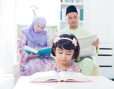 Southeast Asian family reading. Muslim parents and child reading at home.