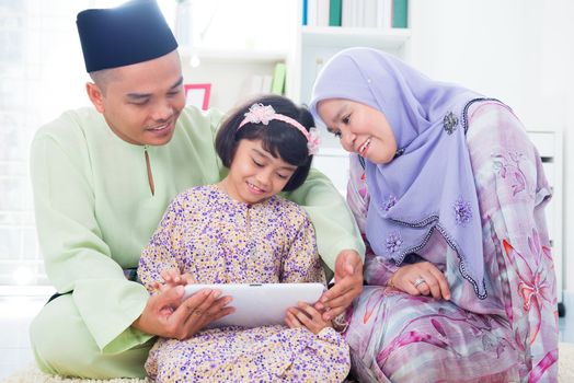 Southeast Asian family using computer internet at home. Muslim family living lifestyle