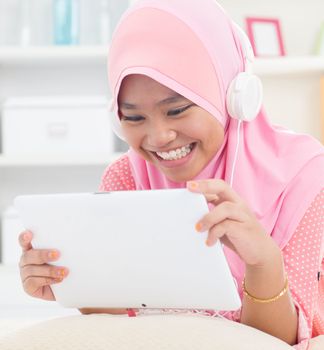 Southeast Asian teenager listen mp3 headphone at home. Muslim teen girl living lifestyle.