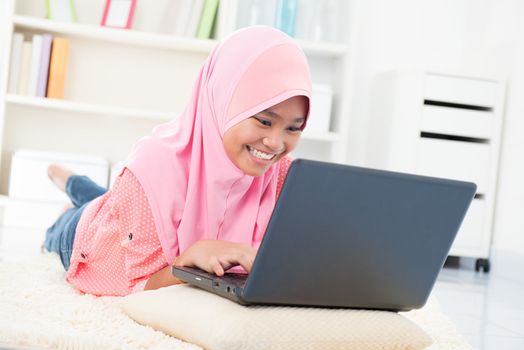 Southeast Asian teenager surfing internet. Muslim teen using notebook at home