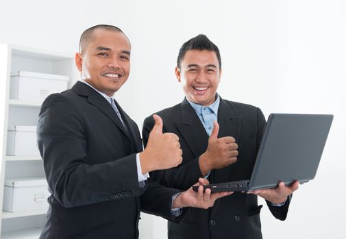 Southeast Asian business people thumbs up, holding notebook in workplace