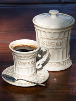 cup of cofee and jar with sugar on the garden wooden table