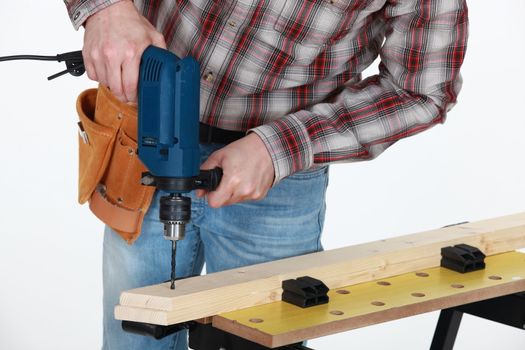 Carpenter drilling into wooden plank