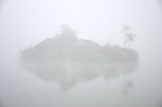 House on island in the lake with foggy background
