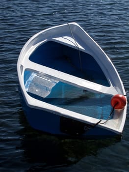 small blue plastic boat sinking after storm