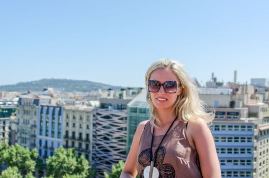 Smiling pretty blonde with sunglasses on roof of a building