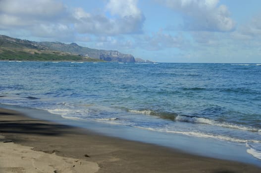 Rugged Hawaiian coastline with beautiful clouds and driftwood at Waihee Beach Park, Maui, Hawaii