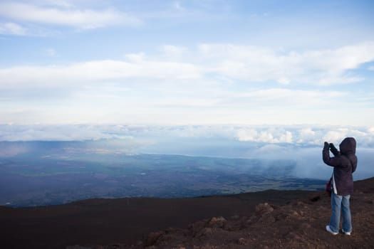 Female on the edge of  Haleakale Volcano (Maui, Hawaii) taking a scenic photograph