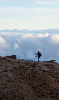 Photographer on the edge of cliff taking photo of sunrise at Haleakala (Maui, Hawaii)