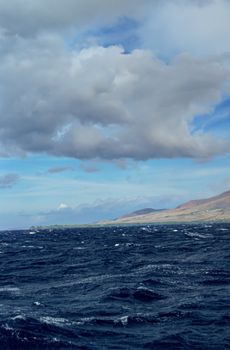 Stormy clouds with rough seas. Maui mountains in the background