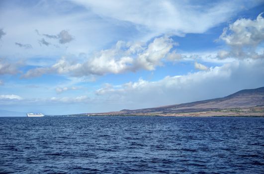 Scenic clouds with small white cruise ship and Maui mountins in background