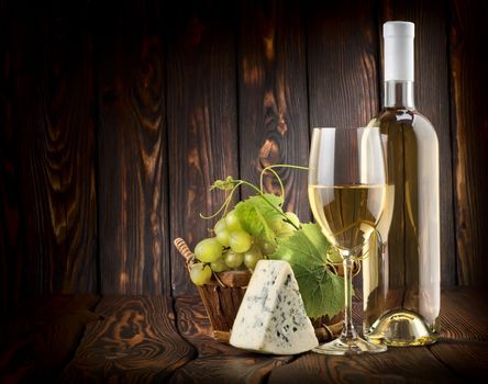 White wine with grapes and blue cheese on a wooden background