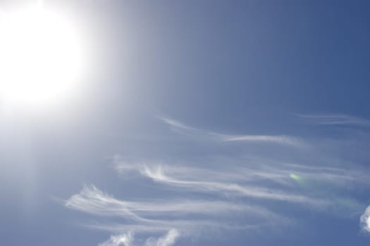 white fluffy clouds and trails against lovely blue sky with bright sun shine