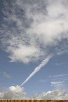 white fluffy clouds and trails against lovely blue sky like wind blowing