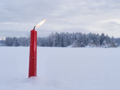 red candles on white snow background outside in winter