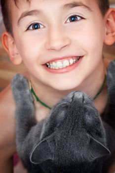 Portrait of a happy boy holding a russian blue kitty