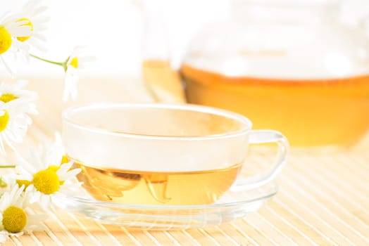 A teacup and a teapot with herbal chamomile tea