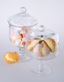 Donut, bun, cookie & glass jar on the background