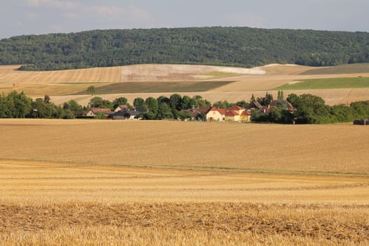 Little countryside village in northern France with harvested wheat fields
