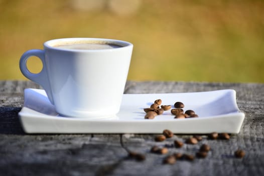 cup of coffee on a plate on a wooden table in daylight