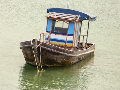 A small wooden fishing boat is floating in the blue sea