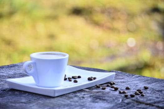 cup of coffee on a plate on a wooden table in daylight