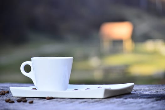 cup of coffee on a plate on a wooden table in daylight