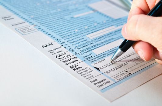 Tax form 1040 with pen in hand.