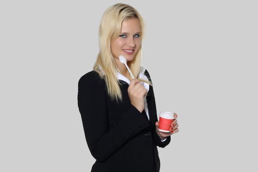 Happy secretary woman with coffee, teaspoon and cup in a gray background