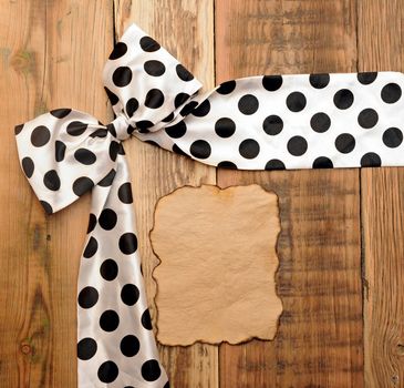 white bow with black dot on wooden background with copyspace for your text