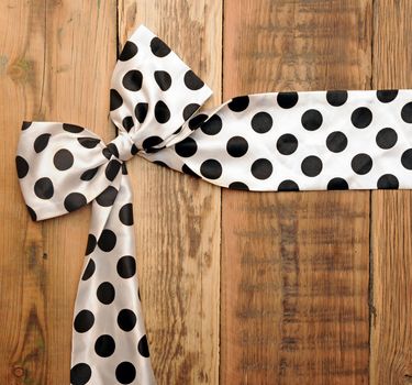 white bow with black dot on wooden background with copyspace for your text