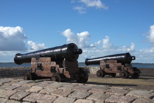 twocannon in the hrabor with boats on th background