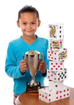 A young girl smiles with a trophy in her hands. She won a card building competition.