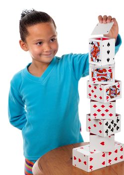 A young girl concentrates whilst laying the final card to complete her playing card tower.