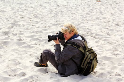 The woman the photographer works sitting on sand