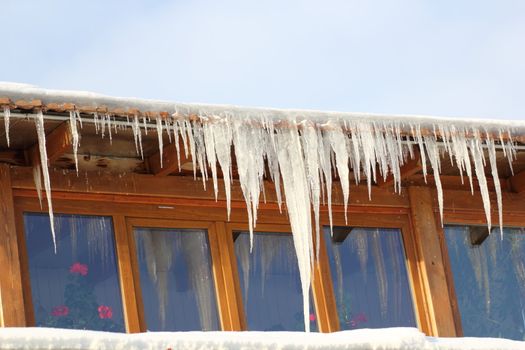 long big icicles on a house roof in a cold winter day