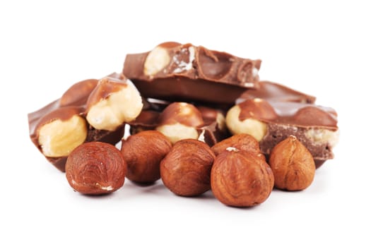 Chocolate pieces and hazelnuts over white background